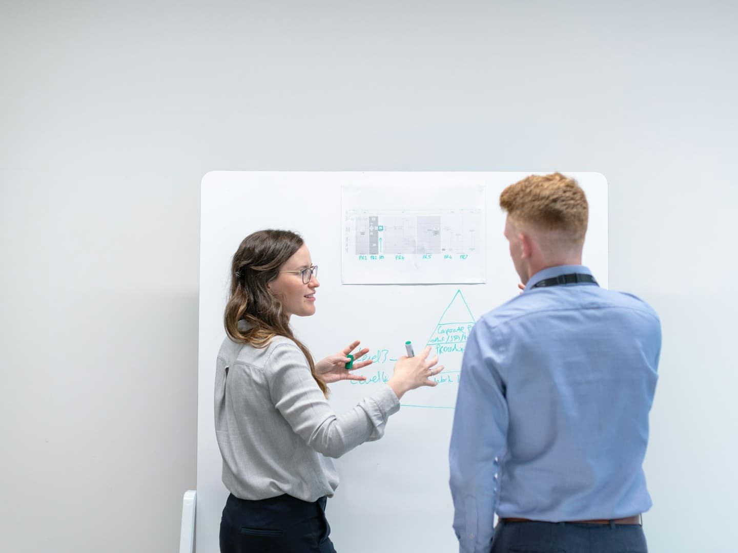 Deux collègues discutent devant un tableau blanc dans un bureau lumineux
